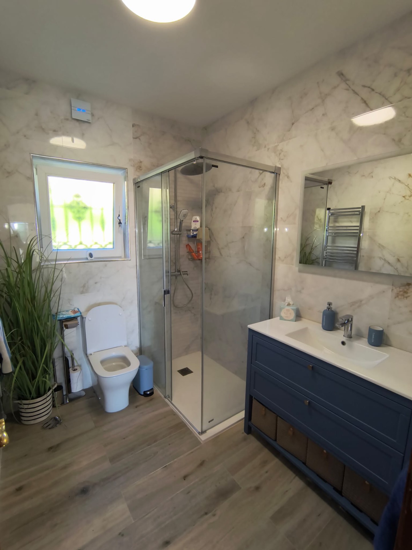 Completed bathroom remodel with marble-effect wall tiles and blue vanity