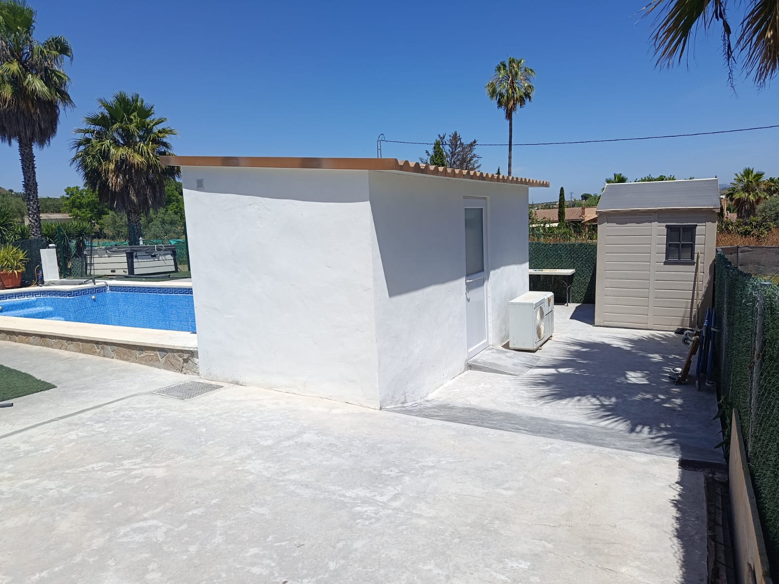 Completed white exterior outbuilding beside a swimming pool